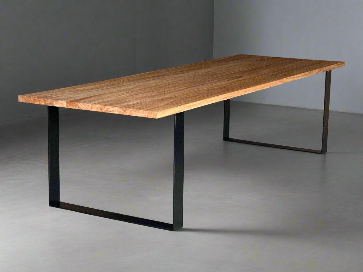A rectangular dining table with a thick wooden top and four straight steel legs at the corners, showcasing a clean industrial style in a contemporary dining setting.