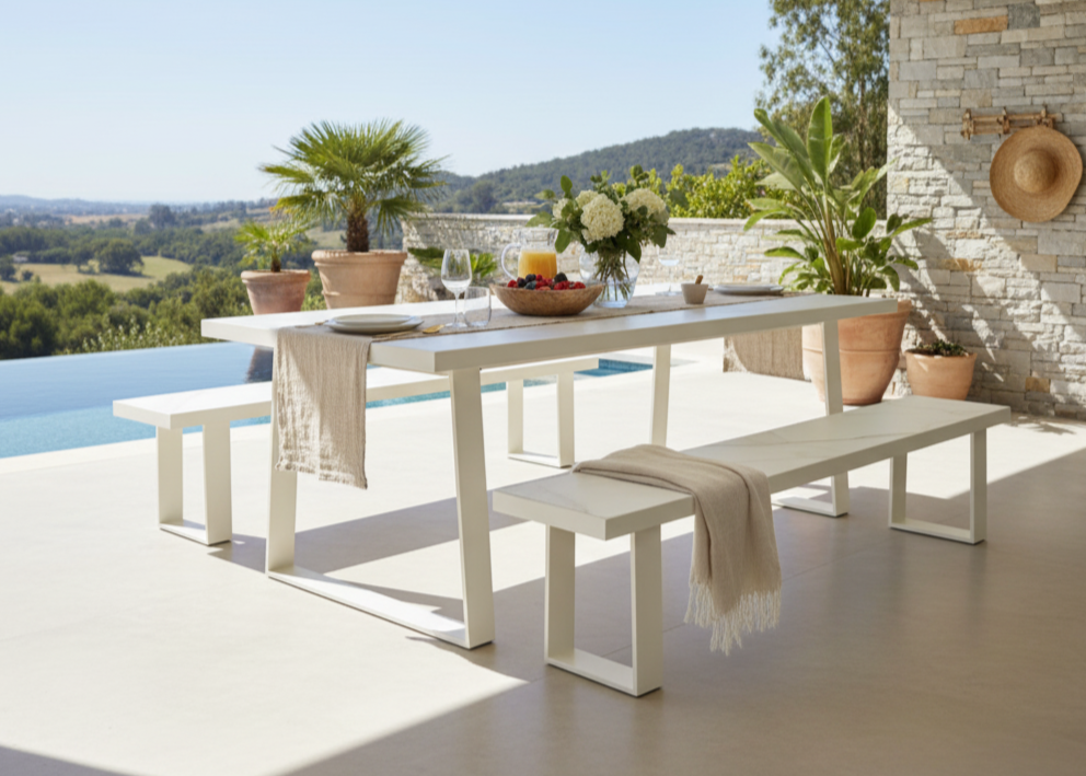 White outdoor dining table with benches beside a pool