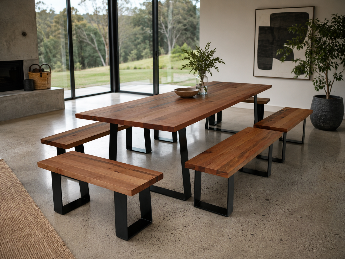 Wooden dining table with benches in a modern room with large windows.