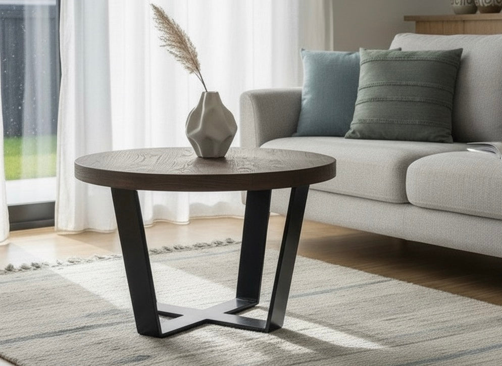 Round coffee table with dark top and black legs in a living room