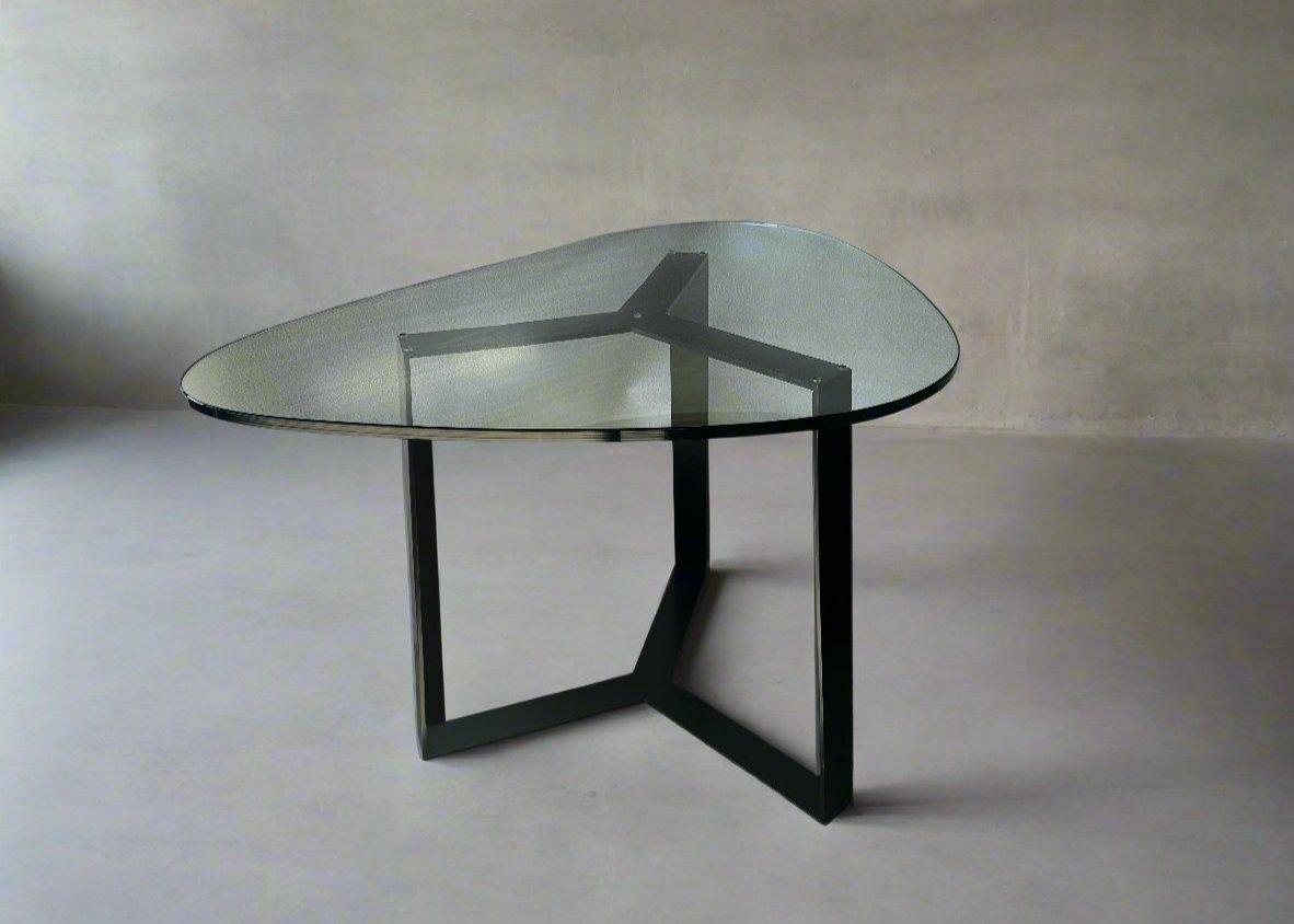 A modern dining table with a clear glass top in a rectangular shape, supported by a minimalist wooden base, allowing the floor and rug to show through for a light, open effect.