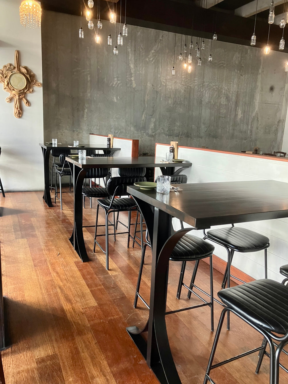 Cafe interior with high tables, stools, wood flooring and a grey wall