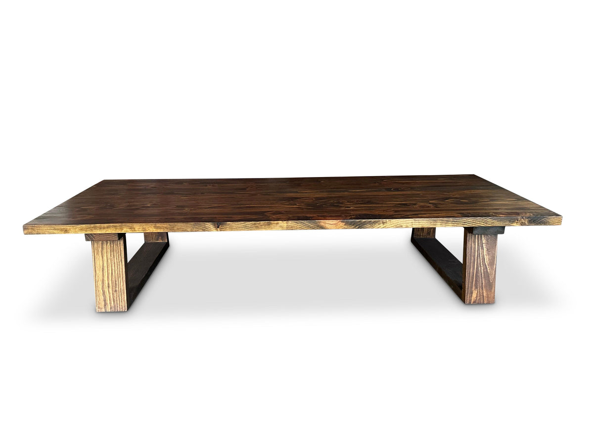 Rectangular low coffee table with dark brown top, block legs and black angled supports