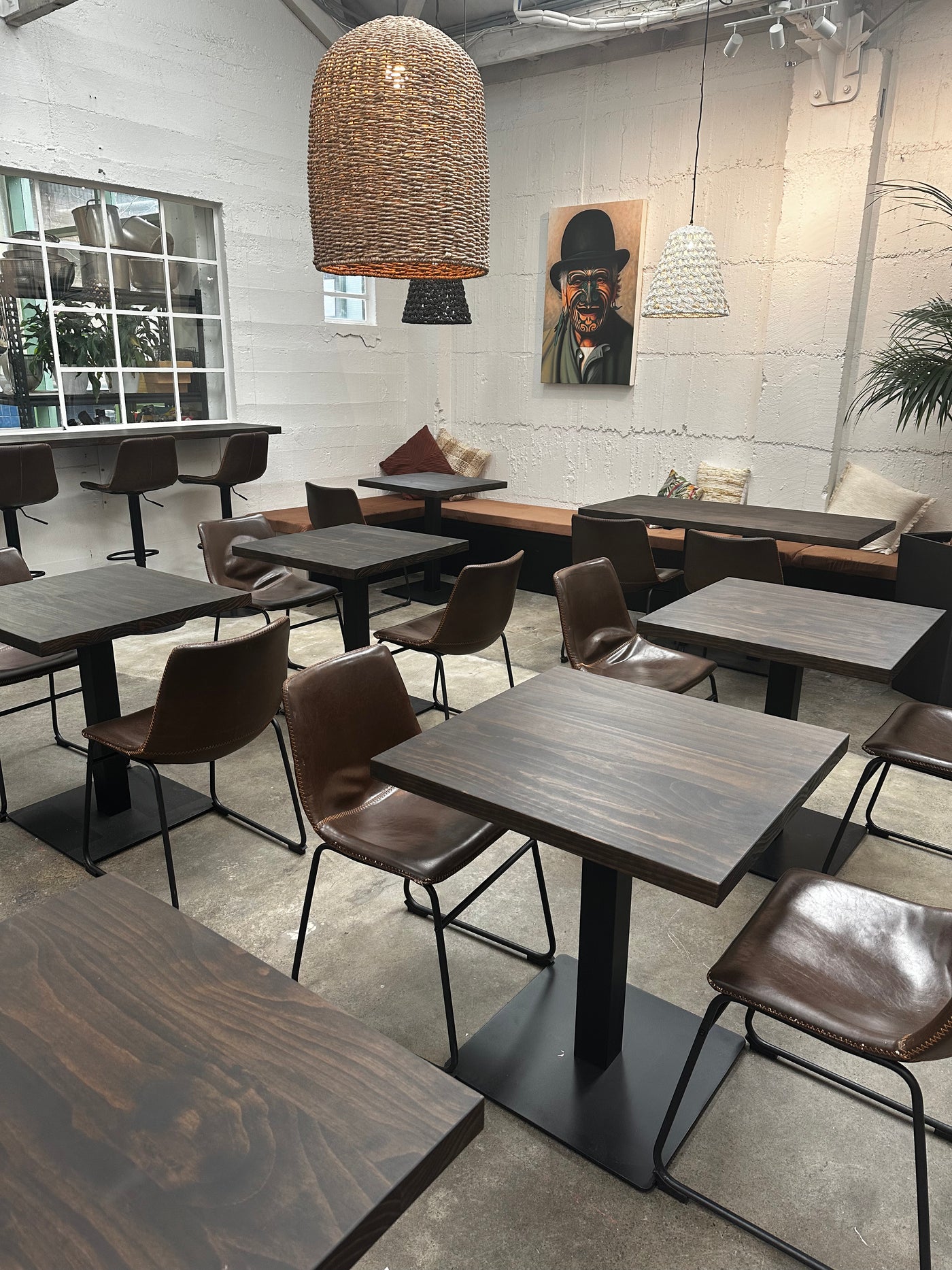 Restaurant seating area with dark tables, chairs, benches and pendant light