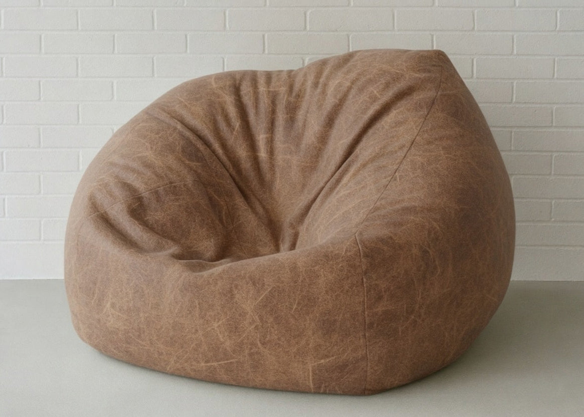 Brown bean bag chair against a white brick wall.