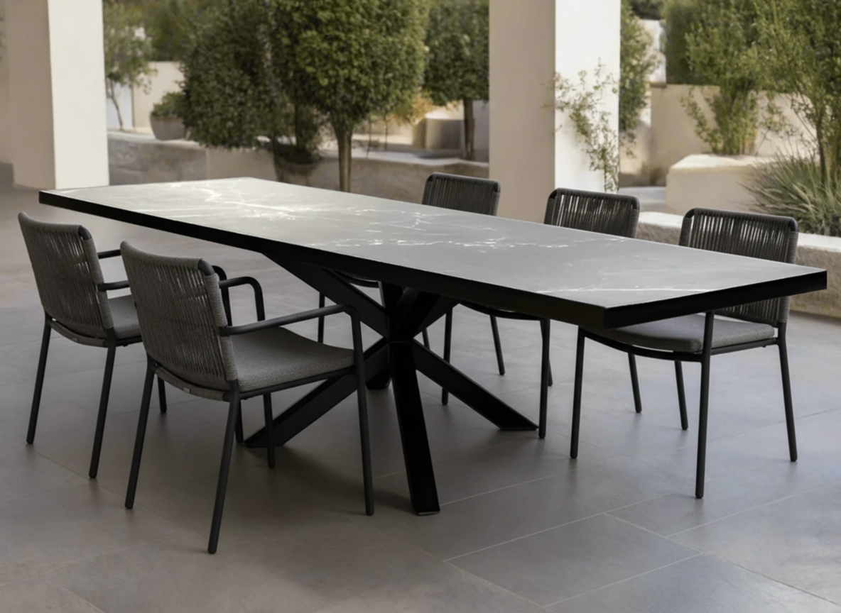 Rectangular outdoor table with grey veined top, black angular base and six chairs on a covered patio