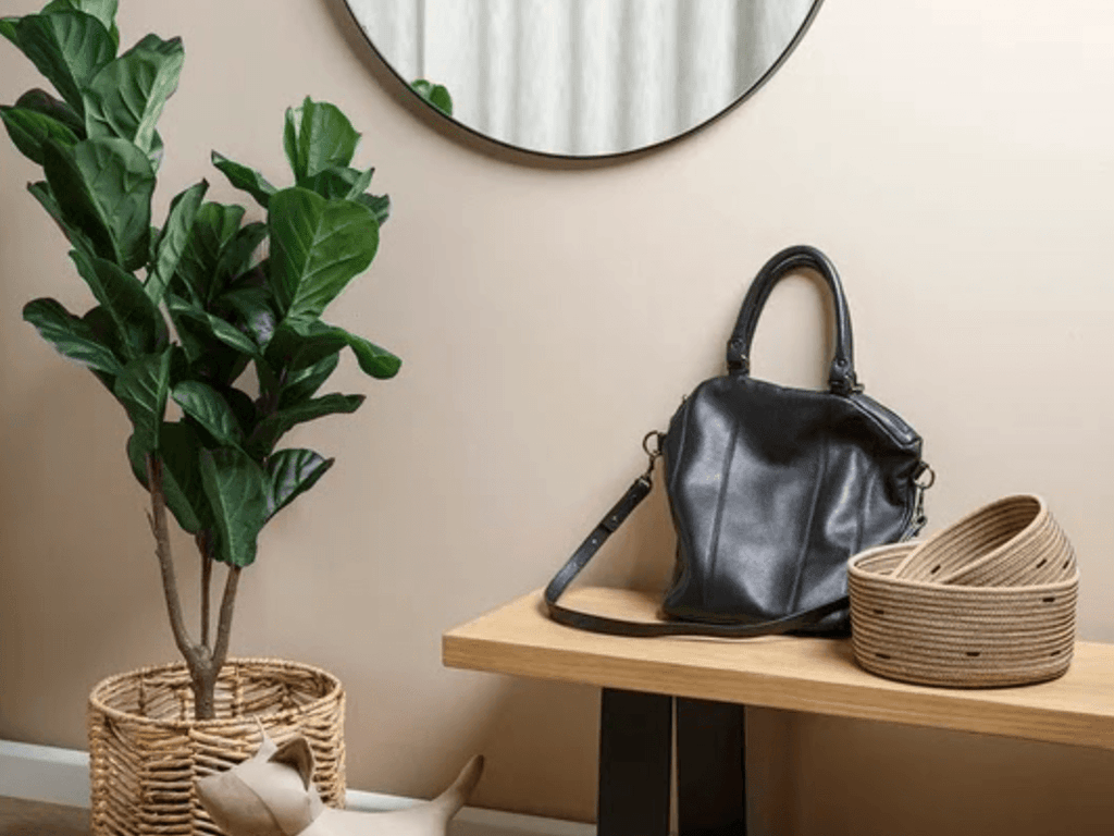 Entryway bench with black legs, bag, basket, shoes, plant and round mirror