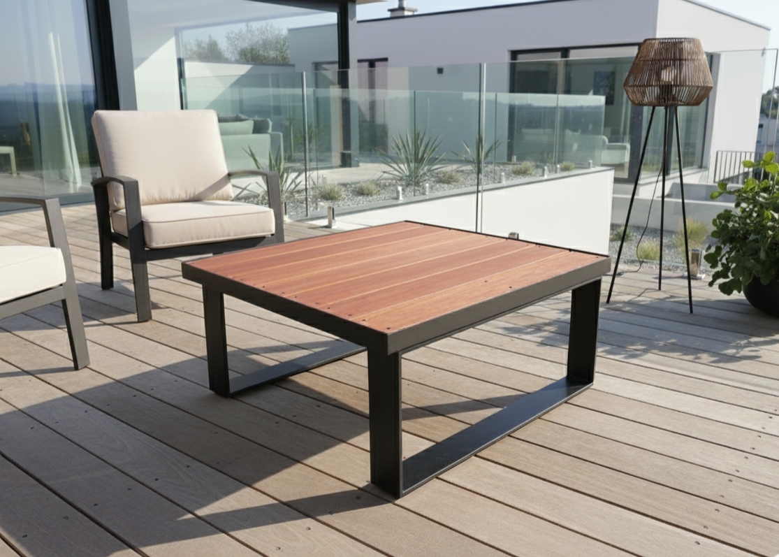Wooden outdoor table on a deck with chairs and a modern building in the background