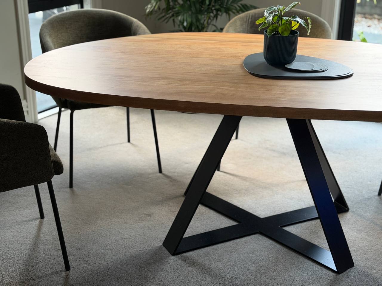 Pebble Crossroads dining table showing black geometric Crossroads base below a rounded West Coast Rimu top